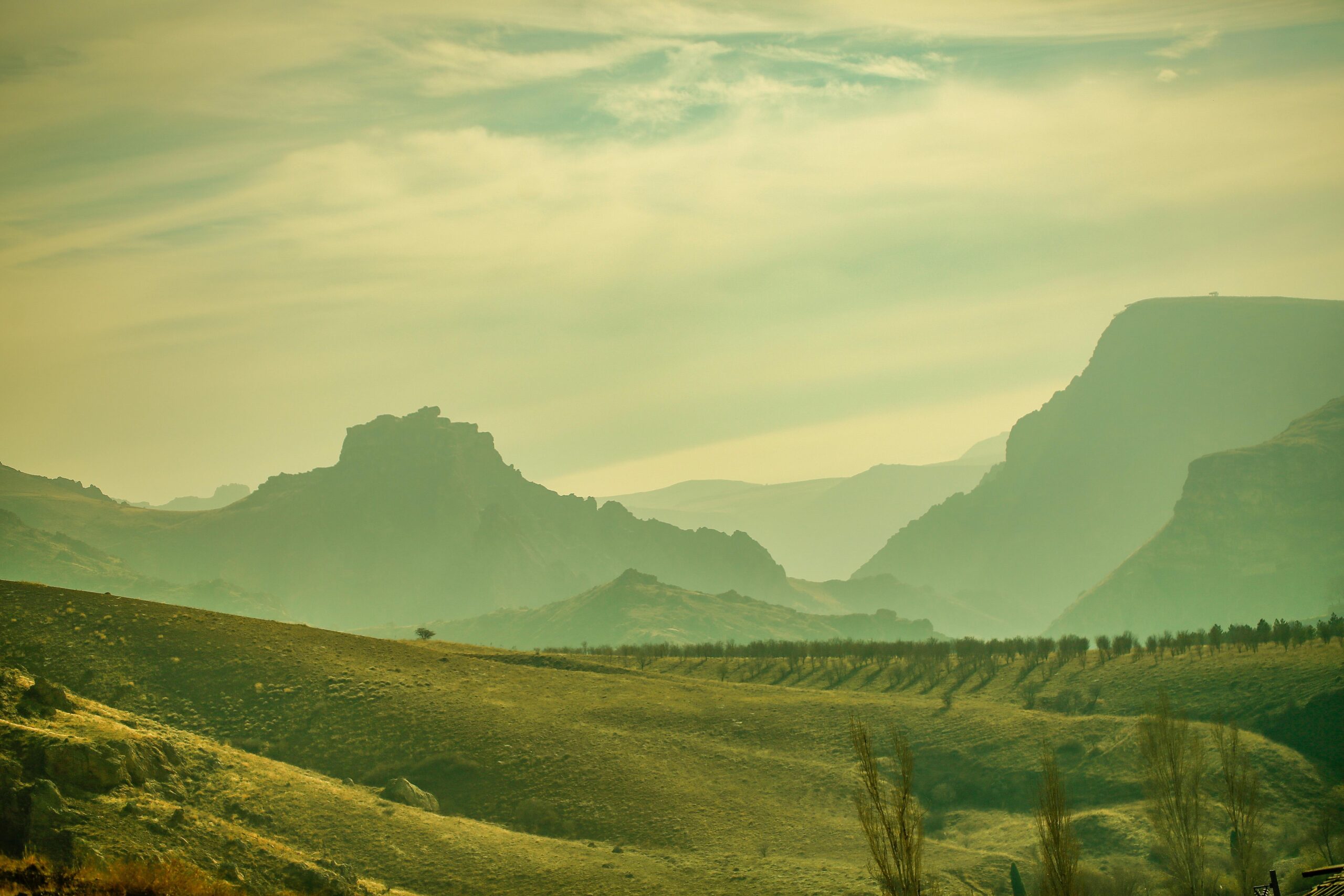 Serene landscape of hills with fog and distant mountains, creating a tranquil atmosphere.