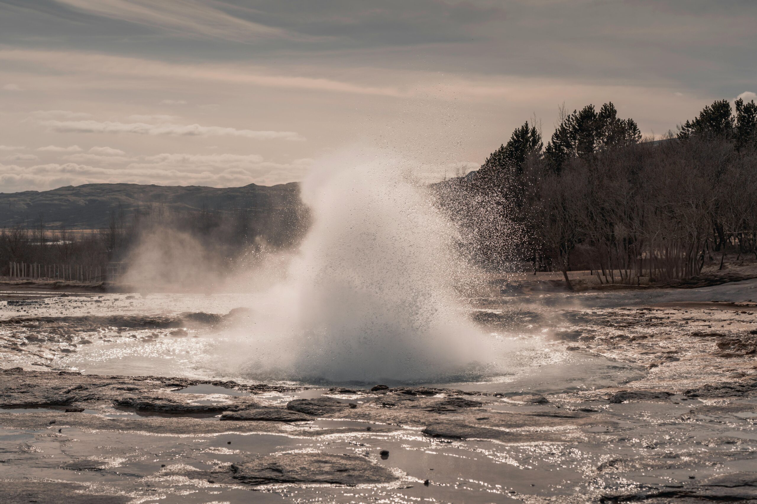 Dramatic eruption of a geyser set against Iceland's rugged, natural backdrop.