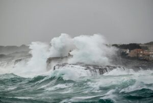Powerful waves crash against the rocky shoreline in Portocolom, capturing the essence of nature's fury.