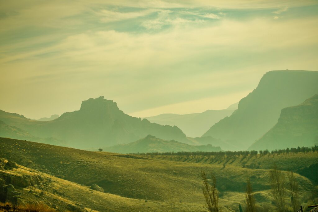 Serene landscape of hills with fog and distant mountains, creating a tranquil atmosphere.