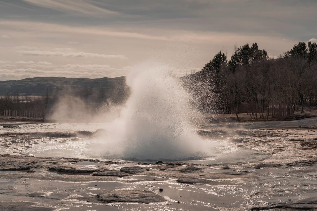 Dramatic eruption of a geyser set against Iceland's rugged, natural backdrop.