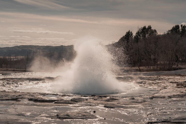 Dramatic eruption of a geyser set against Iceland's rugged, natural backdrop.